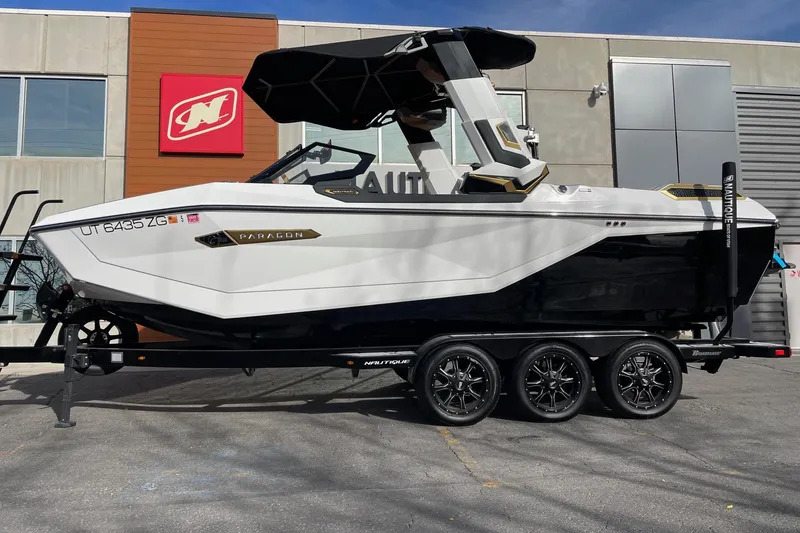 The Image of 2024 Nautique Super Air Nautique G23 Paragon boat on trailer, parked outside a building. - 1