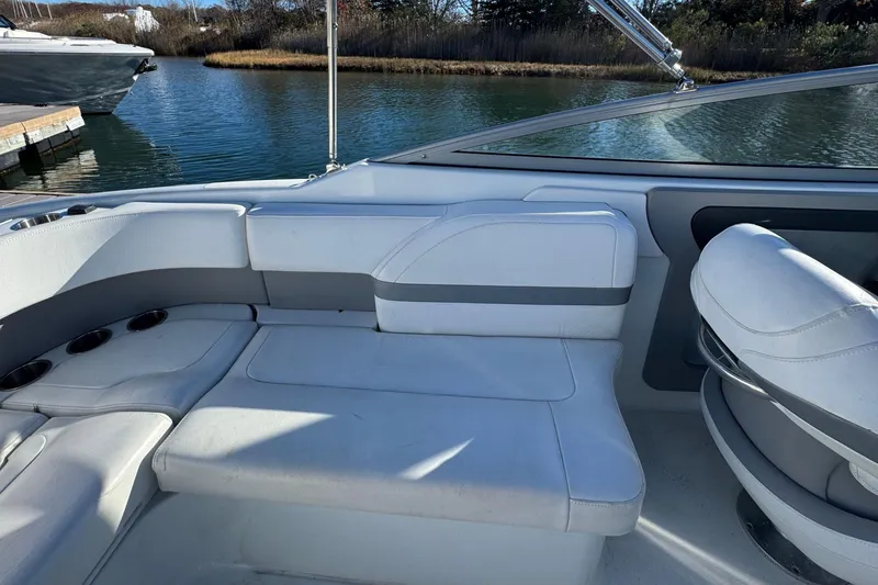 Slide: The Image of 2012 Formula 270 Bowrider interior with white seating, docked by a serene waterway. - 7