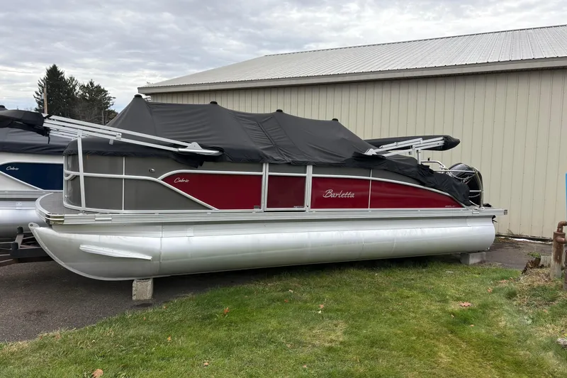 The Image of 2023 Barletta C22UC pontoon boat with cover, parked outdoors near a building. - 1