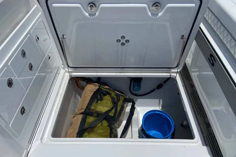 Slide: The Image of Open storage compartment on 2026 Sportsman Open 322 Center Console boat with gear and bucket. - 12