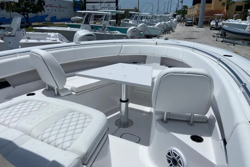 Slide: The Image of 2026 Sportsman Open 322 Center Console boat with white seating and table in marina. - 24