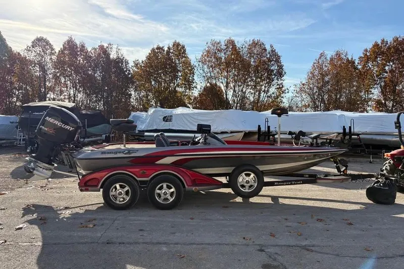 Slide: The Image of 2011 Ranger Z118 Comanche boat on trailer, parked outdoors with trees in background. - 6