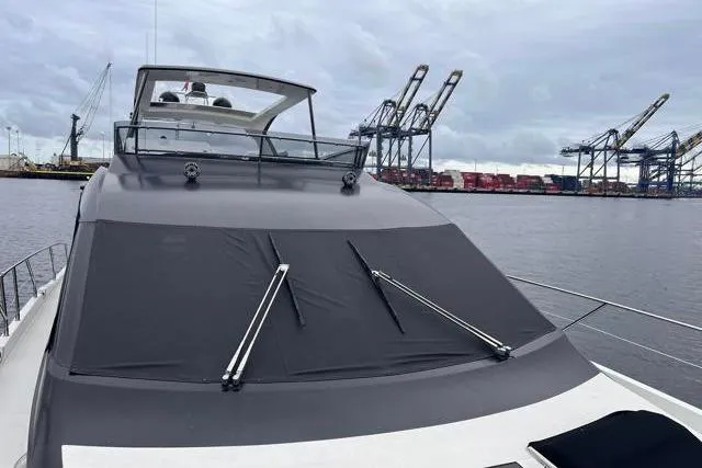 Slide: The Image of 2016 Galeon 660 Flybridge yacht docked at a port with cranes in the background. - 15