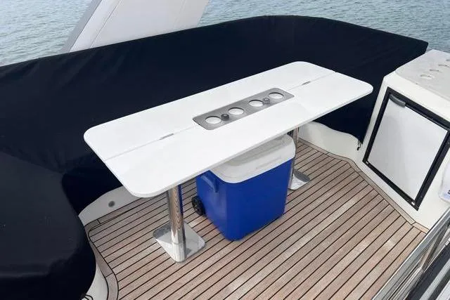 Slide: The Image of Galeon 660 Flybridge 2016 yacht deck with table, cooler, and seating area. - 18