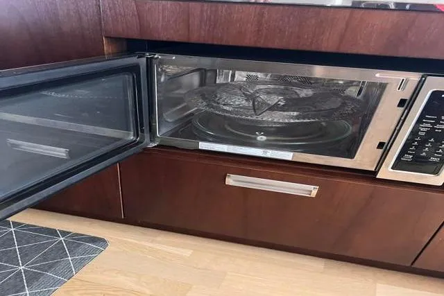 Slide: The Image of Open microwave in Galeon 660 Flybridge yacht kitchen, 2016 model, with wooden cabinetry. - 30
