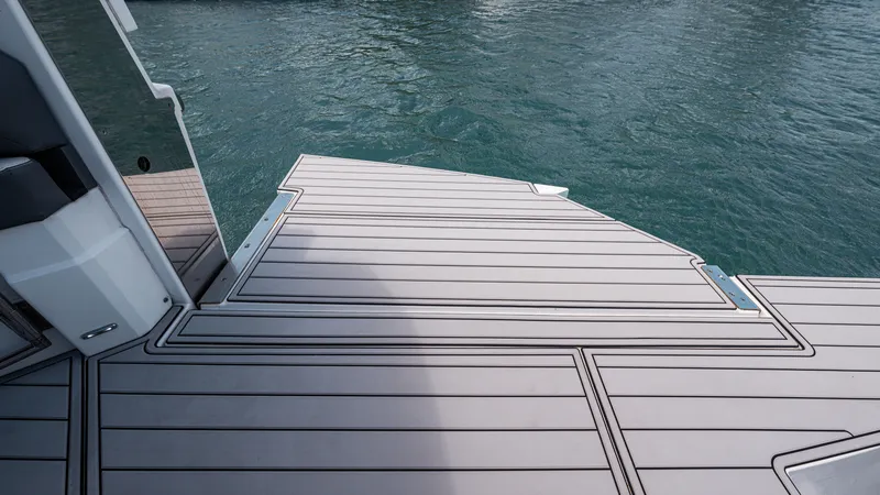 Slide: The Image of 2020 Cruisers Yachts 38 GLS OB swim platform with sleek decking, overlooking calm blue water. - 18