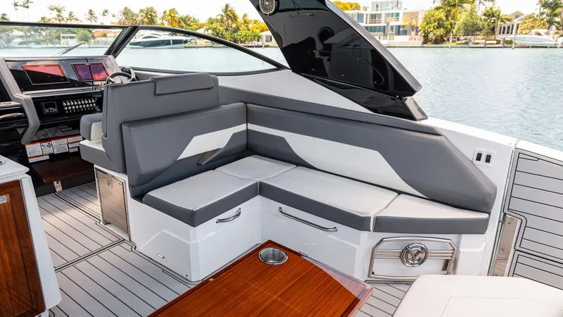 Slide: The Image of 2020 Cruisers Yachts 38 GLS OB interior with gray seating and wooden table by the water. - 25