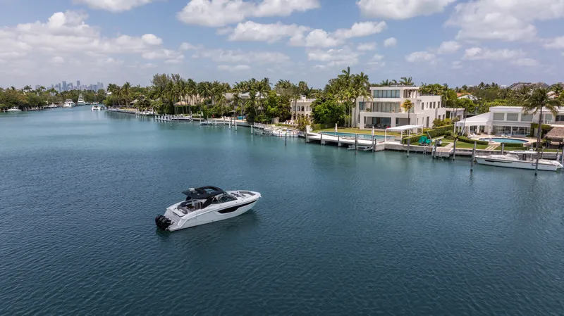 Slide: The Image of 2020 Cruisers Yachts 38 GLS OB on serene waterfront with luxury homes and palm trees. - 9