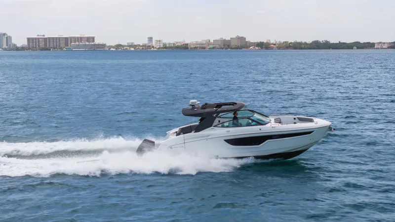 Slide: The Image of 2020 Cruisers Yachts 38 GLS OB speeding on open water, cityscape in background. - 13