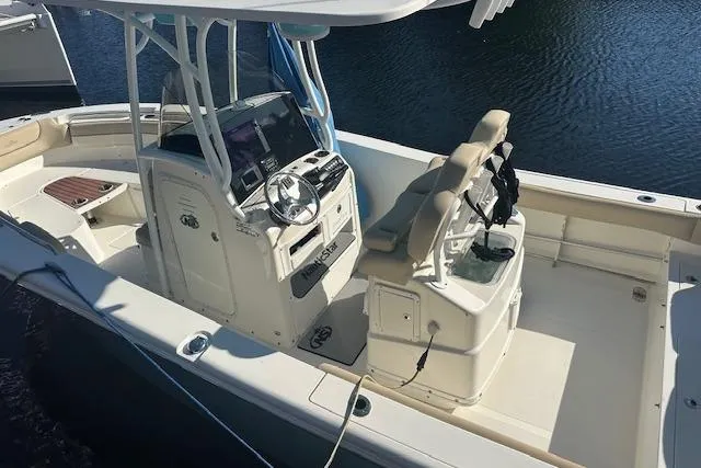 Slide: The Image of 2018 NauticStar 2602 Legacy boat interior with helm and seating, docked on water. - 3