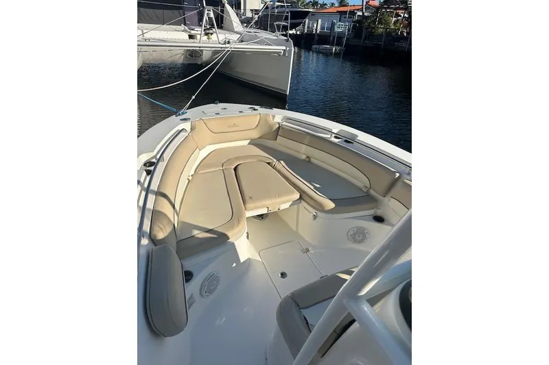 Slide: The Image of 2018 NauticStar 2602 Legacy boat interior with beige seating in a marina. - 5