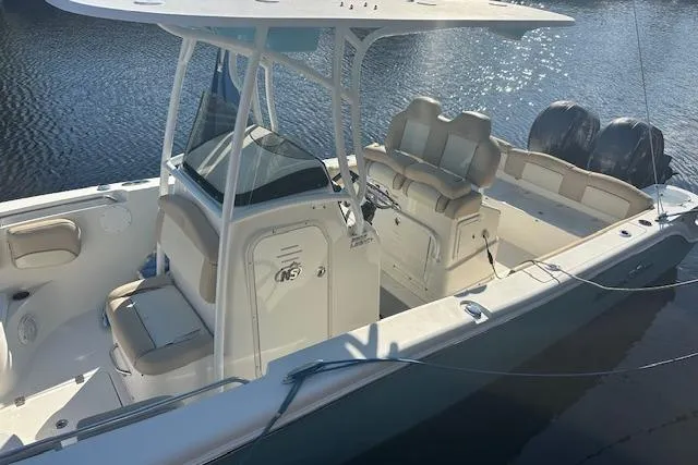 Slide: The Image of 2018 NauticStar 2602 Legacy boat with dual engines, docked on calm water. - 6