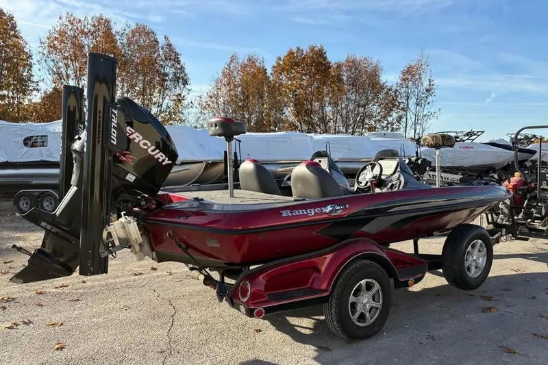 Slide: The Image of 2011 Ranger Z118 Comanche boat with Mercury engine, parked outdoors in autumn setting. - 4