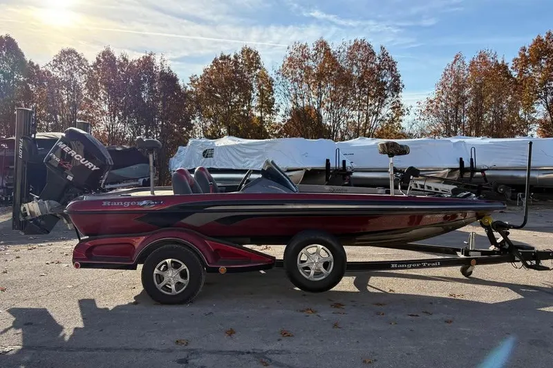 Slide: The Image of 2011 Ranger Z118 Comanche bass boat on trailer, parked outdoors with autumn trees. - 6