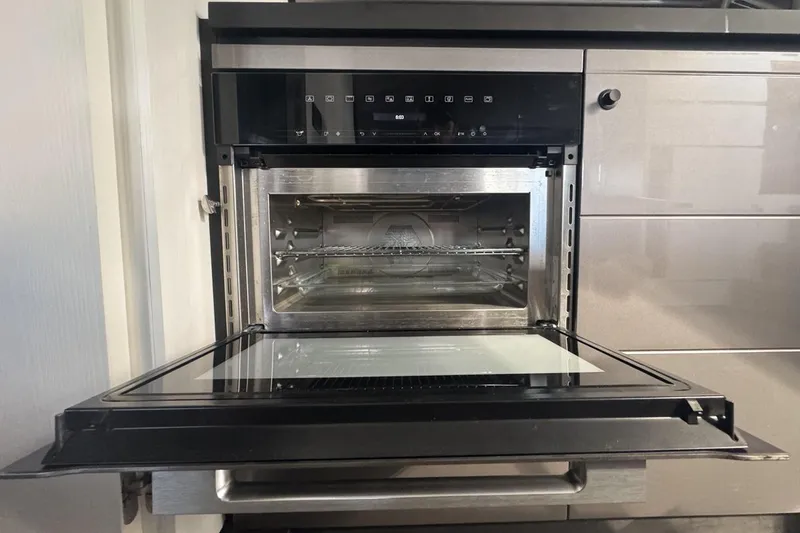 Slide: The Image of Modern kitchen oven with open door, showcasing sleek stainless steel interior and digital controls. - 84