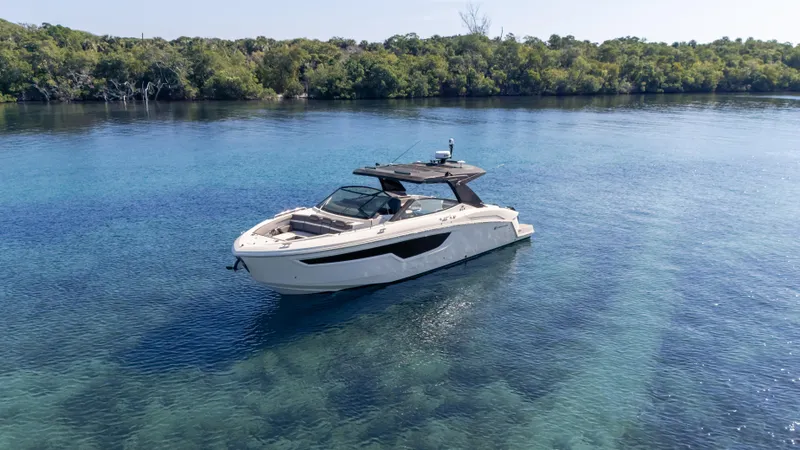 Slide: The Image of 2021 Cruisers Yachts 38 GLS OB 450R on clear blue water near lush shoreline. - 9