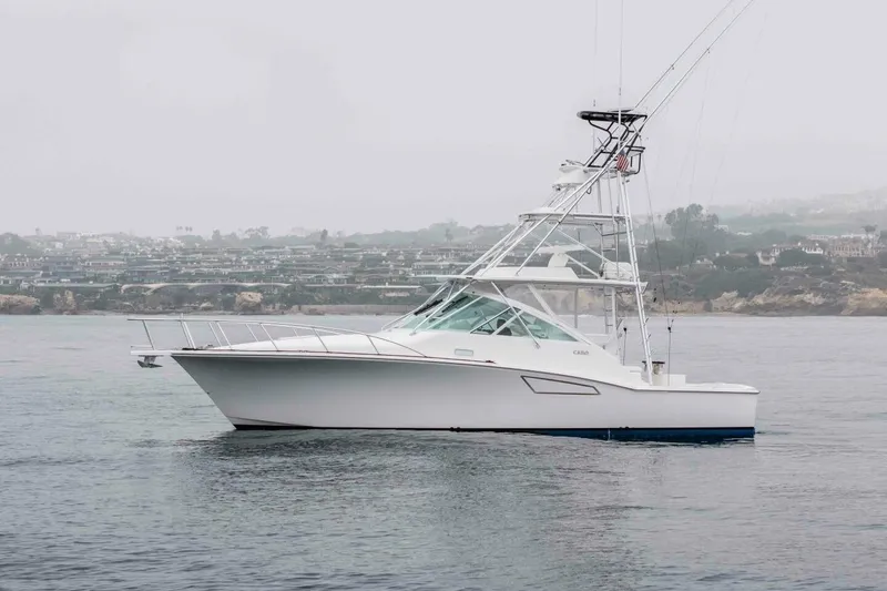 Slide: The Image of 2008 Cabo Yachts 38 EXPRESS fishing boat on calm waters, coastal background. - 28