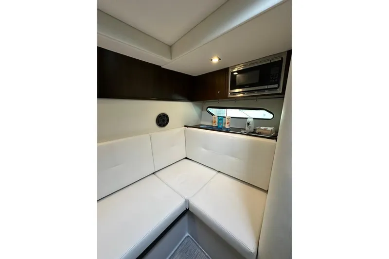 Slide: The Image of 2021 Cruisers Yachts 338 South Beach Edition interior with white seating and kitchenette. - 14