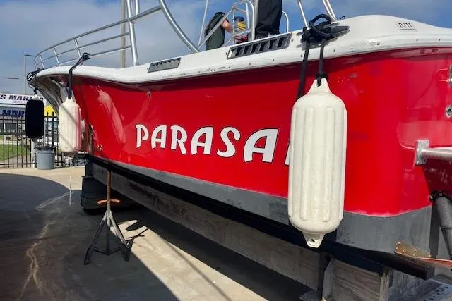 Slide: The Image of Red 2015 Comercial Water Sports Ocean Pro 31 boat with "PARASA" text, docked with fenders. - 2