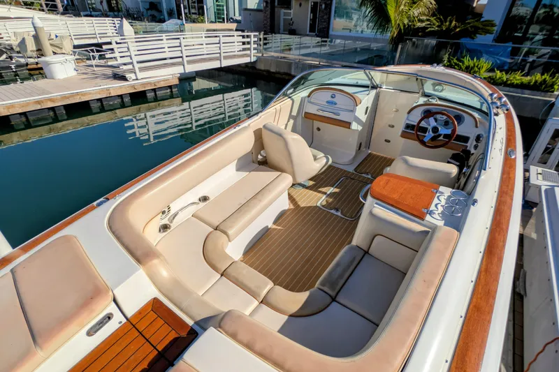 Slide: The Image of 2008 Chris-Craft Launch 25 boat interior with elegant seating and wooden accents at a marina. - 2