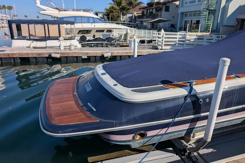 Slide: The Image of 2008 Chris-Craft Launch 25 boat docked, covered with a blue tarp, near waterfront homes. - 4