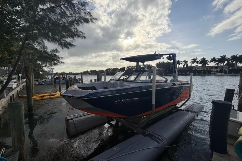 The Image of 2022 Nautique Super Air Nautique G25 boat docked by waterfront under cloudy sky. - 0