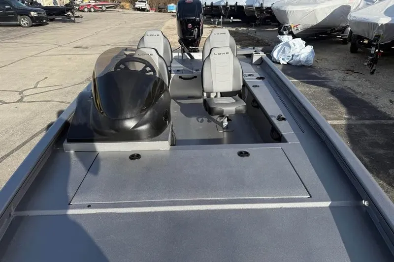 Slide: The Image of 2026 Lowe Outlet 20 boat with dual seats and steering console in a parking lot. - 13