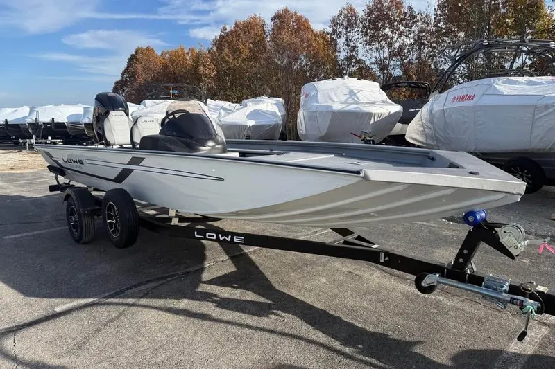 Slide: The Image of 2026 Lowe Outlet 20 boat on trailer, parked outdoors with covered boats in background. - 3