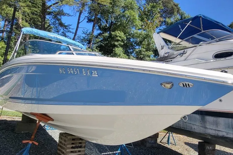 The Image of 2022 Chaparral 23 SSi boat on stands, blue and white hull, outdoors. - 0