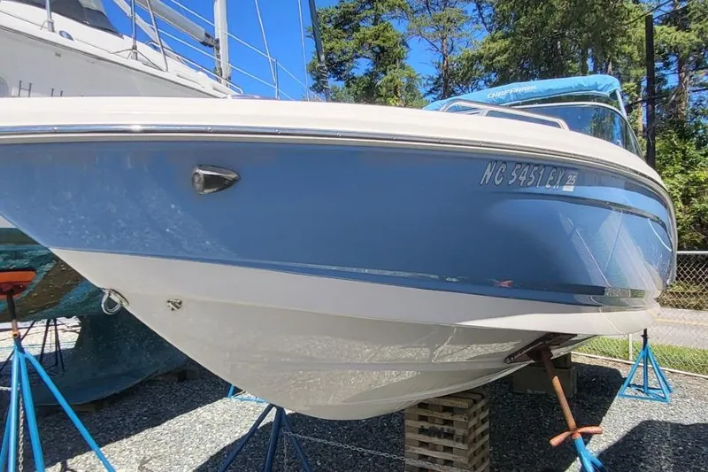 Slide: The Image of 2022 Chaparral 23 SSi boat on stands, blue and white hull, sunny day. - 2