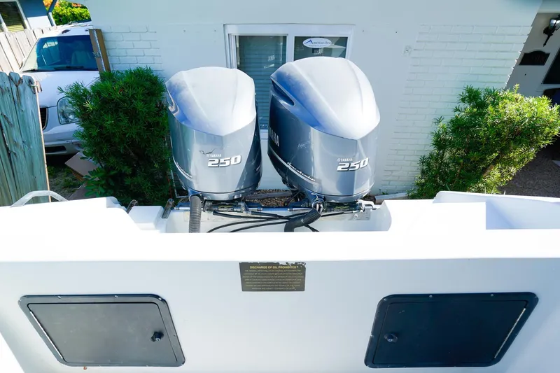 Slide: The Image of 2005 Boston Whaler 260 Justice with twin Yamaha 250 engines, parked near a white building. - 4