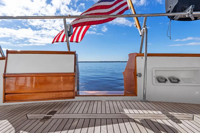 Slide: The Image of 2006 Grand Banks Europa 47 yacht deck with American flag, overlooking serene ocean view. - 22