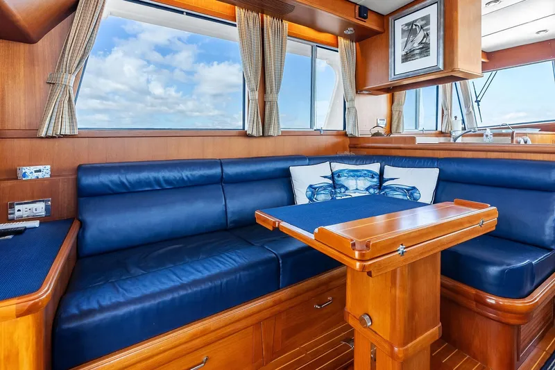 Slide: The Image of Luxurious 2006 Grand Banks Europa 47 yacht interior with blue leather seating and wooden table. - 27