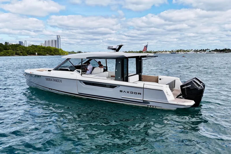 Slide: The Image of 2025 Saxdor 400 GTO boat cruising on a sunny day with city skyline backdrop. - 11