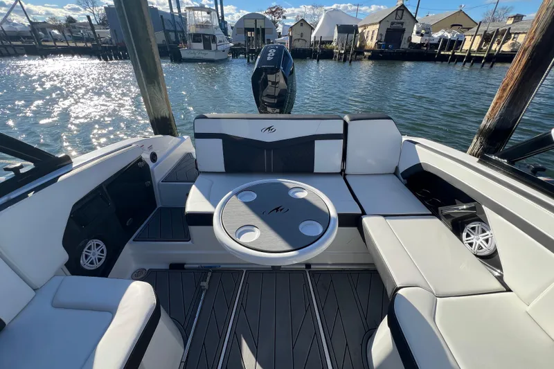Slide: The Image of 2023 Monterey 275SS Super Sport boat interior with seating and table, docked by the water. - 12