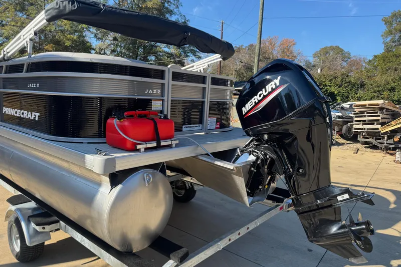 Slide: The Image of 2026 Princecraft Jazz 17 pontoon boat with Mercury outboard motor on trailer. - 2