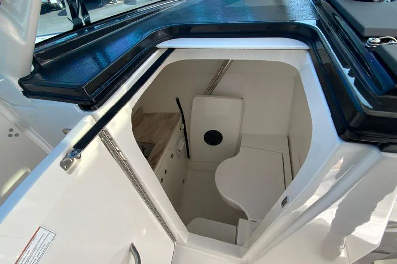Slide: The Image of 2024 Pursuit DC 326 Dual Console boat bathroom with modern white toilet and storage. - 28