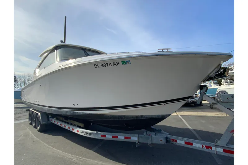 Slide: The Image of 2024 Pursuit DC 326 Dual Console boat on trailer, parked outside dealership. - 3
