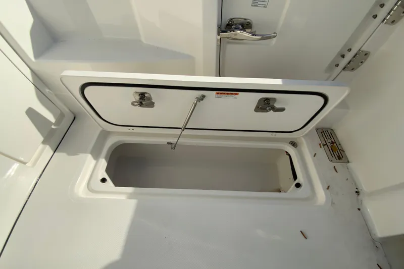 Slide: The Image of 2024 Pursuit DC 326 Dual Console storage compartment with open hatch, revealing interior equipment. - 46