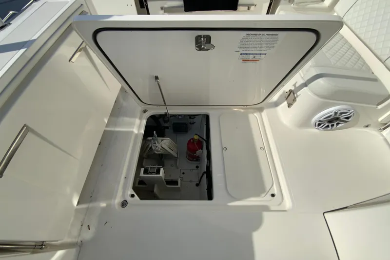 Slide: The Image of 2024 Pursuit DC 326 Dual Console boat storage compartment with fire extinguisher and anchor. - 47