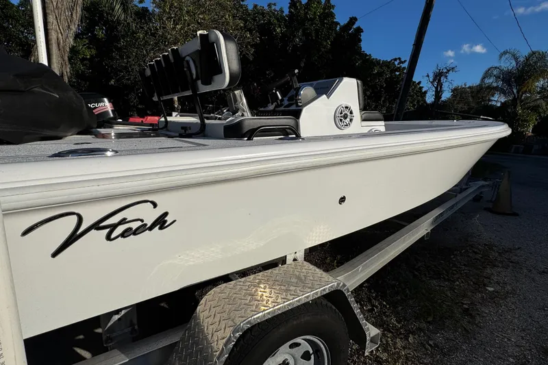 Slide: The Image of 2024 Vtech 18 boat on trailer, side view with logo, outdoors. - 10