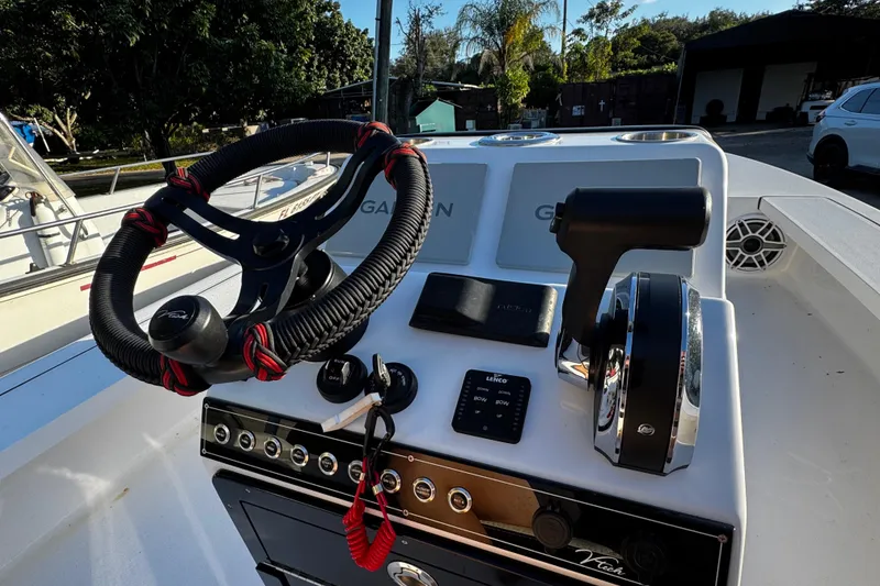 Slide: The Image of 2024 Vtech 18 boat dashboard with steering wheel and controls, surrounded by trees and vehicles. - 19