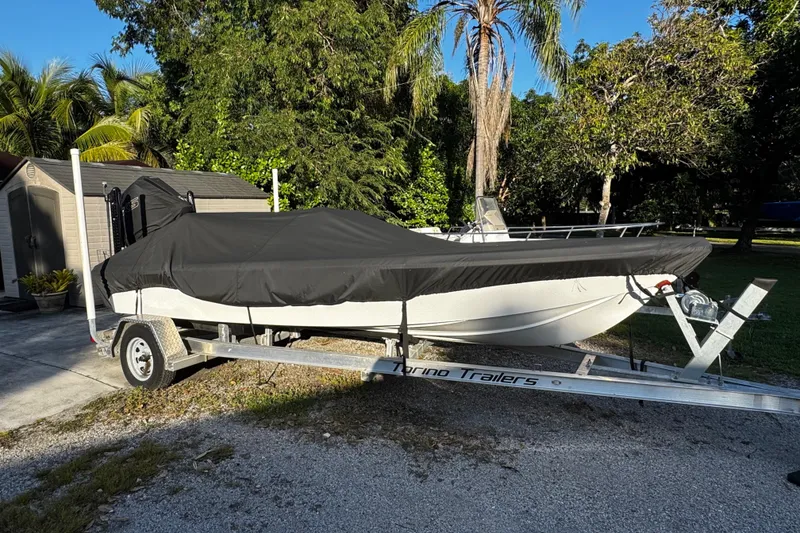 Slide: The Image of Covered Vtech 18 boat on trailer, surrounded by lush greenery, 2024 model. - 8