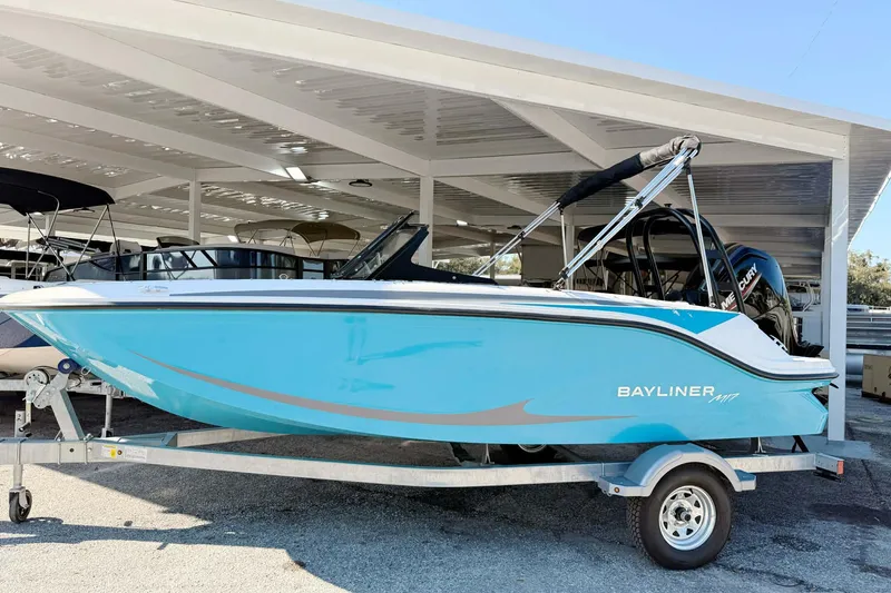 The Image of 2026 Bayliner M17 boat in blue on a trailer under a covered area. - 0
