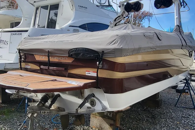 Slide: The Image of 2021 Centurion Ri265 boat with cover, docked alongside other vessels. - 15