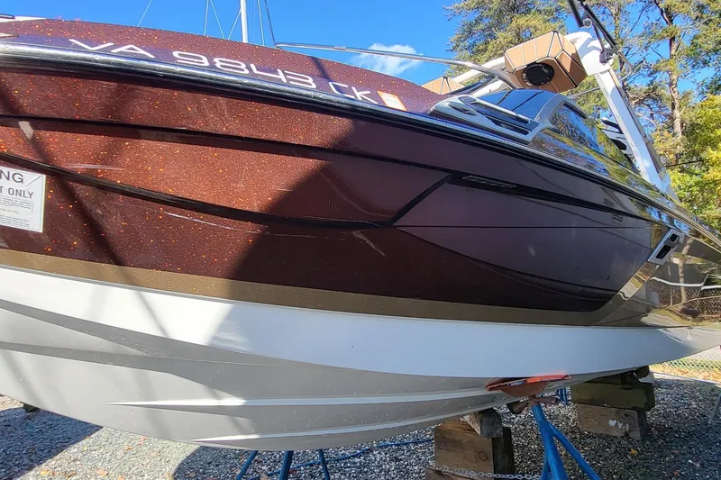 Slide: The Image of 2021 Centurion Ri265 boat with a sleek, glossy brown exterior on display. - 6