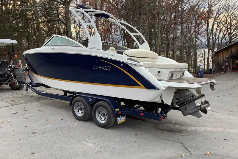 Slide: The Image of 2014 Cobalt R5 boat on trailer, parked outdoors near trees and a wooden building. - 3