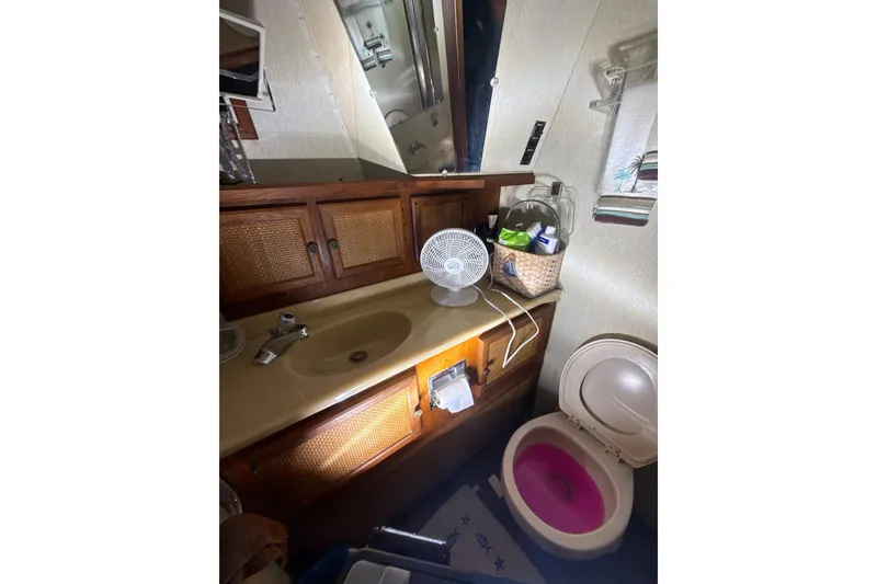 Slide: The Image of 1984 Viking 44 Motor Yacht bathroom with sink, toilet, and storage cabinets. - 107