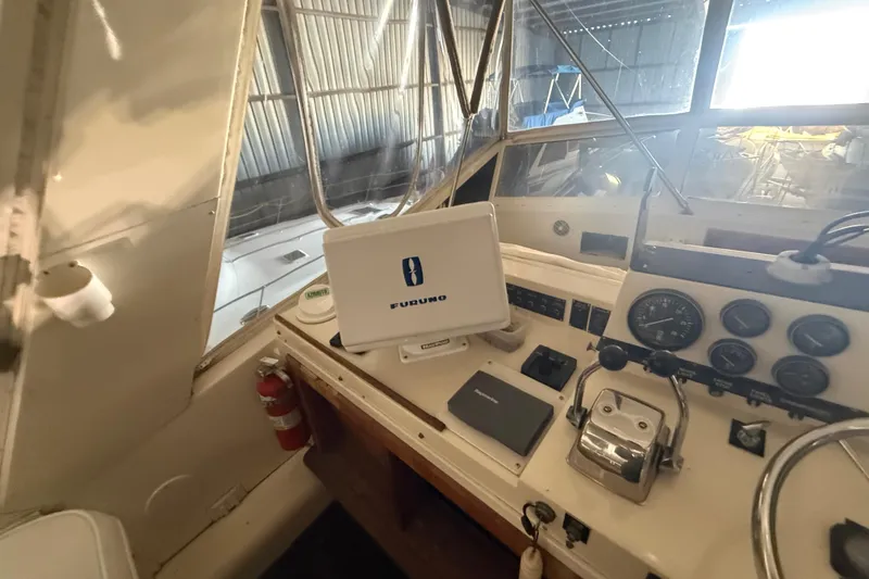 Slide: The Image of 1984 Viking 44 Motor Yacht helm with navigation equipment and gauges in a marina setting. - 37