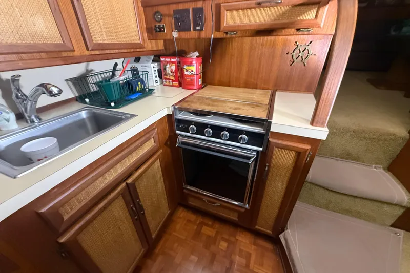 Slide: The Image of 1984 Viking 44 Motor Yacht kitchen with stove, sink, and wooden cabinetry. - 55